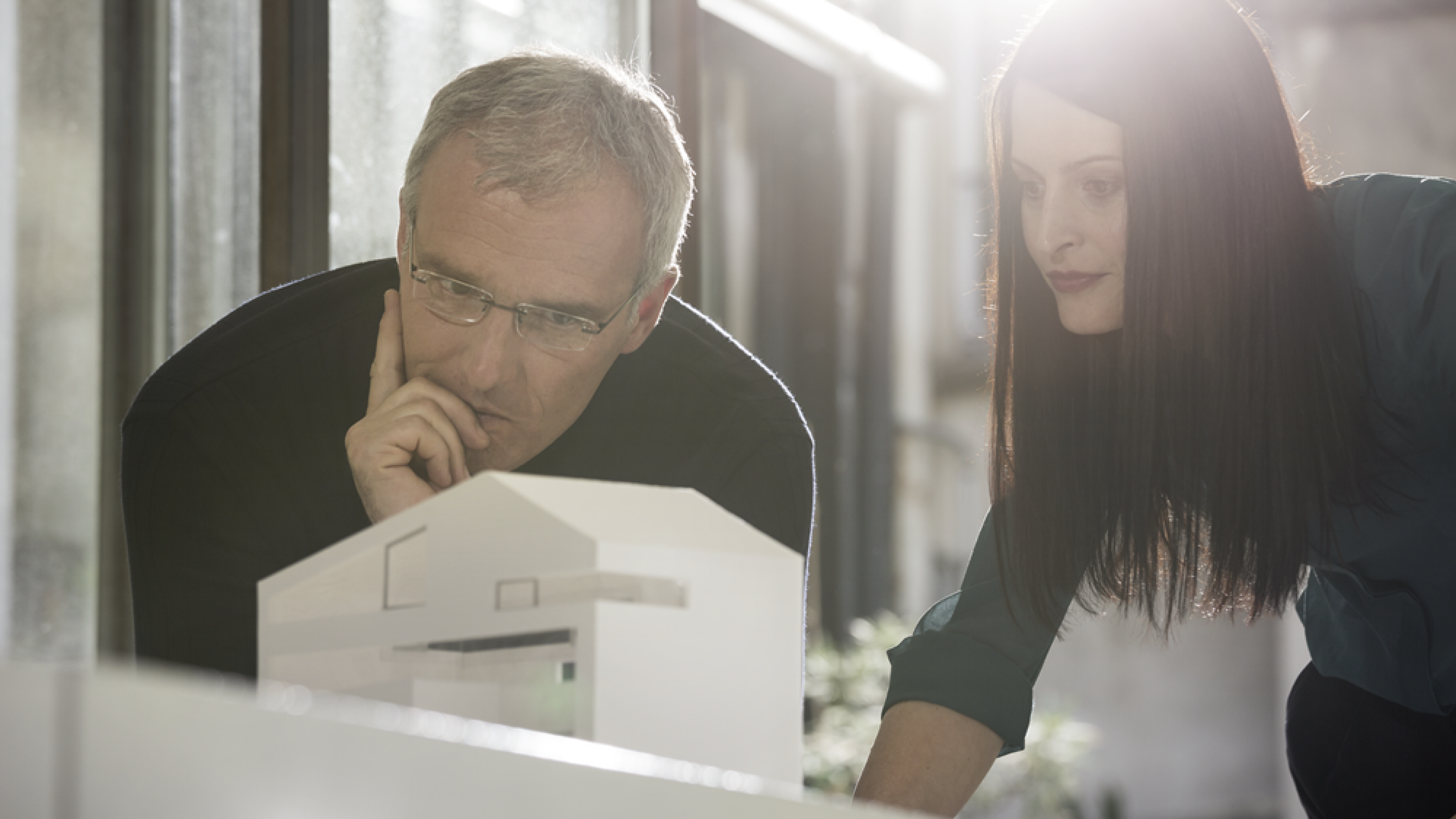 Two people looking at a model building.